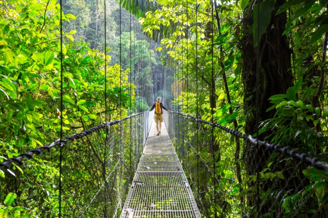 Eine Person auf einer Brücke im Dschungel von Costa Rica als Reiseziel im Mai