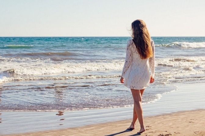 Frau mit langen Haaren am Strand neben Salzwasser 