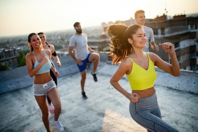 Junge Menschen trainieren bei Sonnenuntergang auf Dachterrasse.