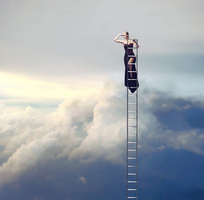 Eine Frau in einem schwarzen Abendkleid steht auf den letzten Sprossen einer Leiter, welche durch die Wolkendecke ragt. 