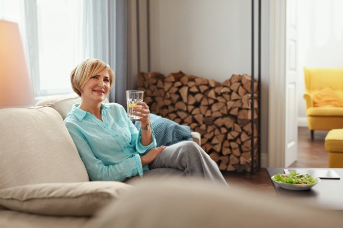 Frau in den Wechseljahren hält ein Glas Wasser für schöne Haut