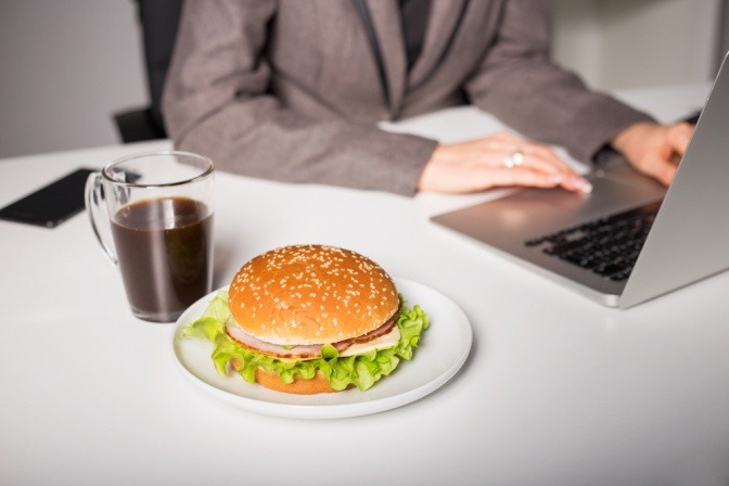 Ein Burger liegt neben einem Laptop