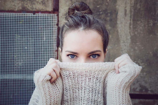 Eine Frau versteckt die unreine Haut unter ihrem Pulli