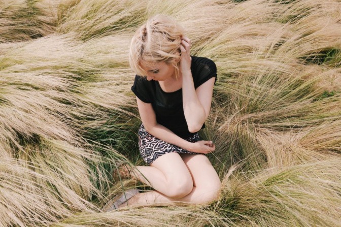 Eine Frau sitzt in wildem trockenen Gras