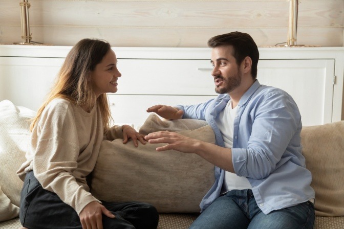 Frau und Mann unterhalten sich angeregt auf Sofa.