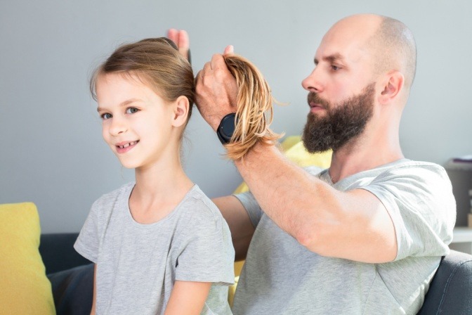 Ein Vater frisiert seiner Tochter die Haare.