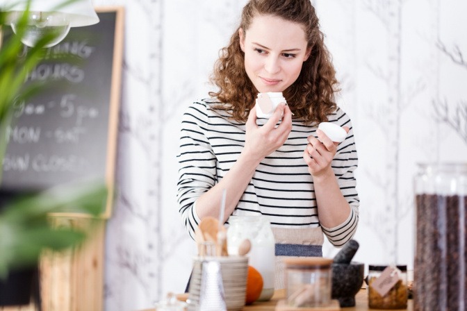 Frau riecht an einem Kosmetikprodukt in einem Glastiegel