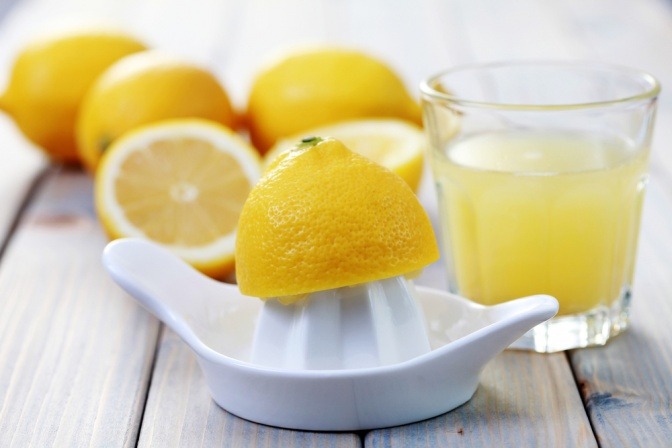 Zitronen liegen neben einem Glas mit Zitronensaft