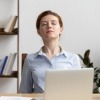 Frau im Büro macht Atemübungen gegen Stress
