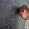 Frustriertes Mädchen lehnt mit Kopf an einer Schiefertafel.