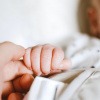 Schlafendes Baby hält finger einer erwachsenen Person