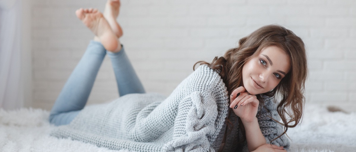 Frau liegt mit einer Strickjacke im Bett