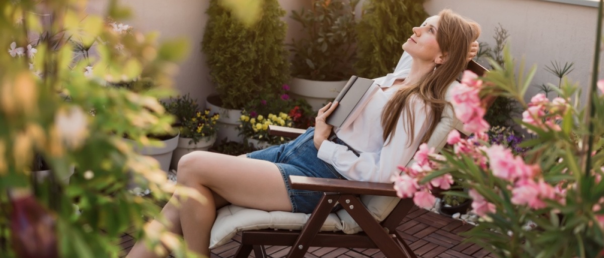 Frau sitzt auf der Veranda und lässt den Alltagsstress hinter sich