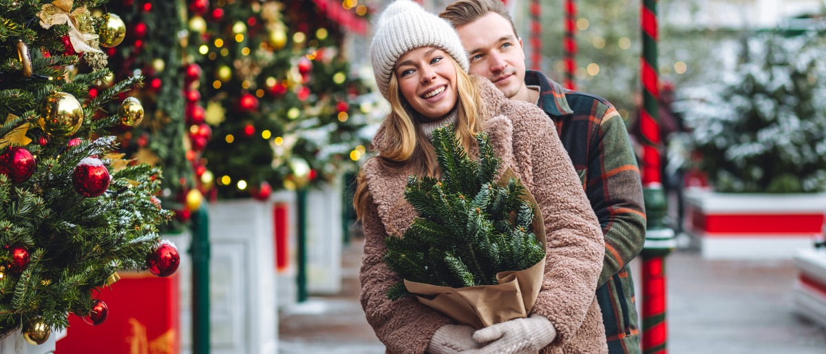 Frau mit ihrem Partner auf dem Weihnachtsmarkt in einem warmen Wintermantel