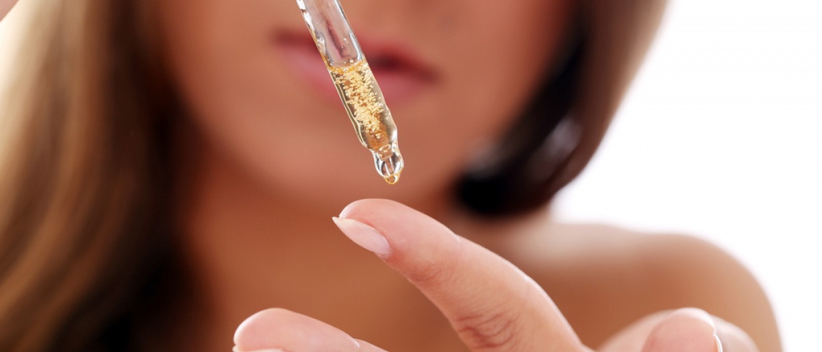 Eine Frau gibt mit einer Pipette Öl für Haut auf ihren Finger