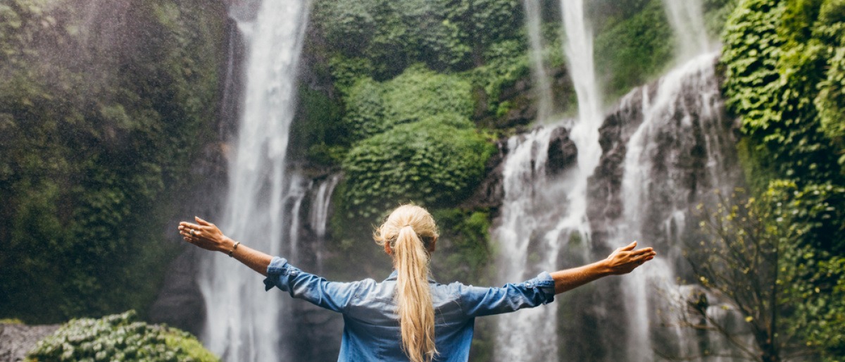 Eine Frau steht vor einem Wasserfall