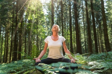 Frau beim Waldbaden in der Übung Meditation