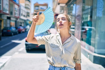 Junge Frau mit Fächer sorgt für Erfrischung im Sommer