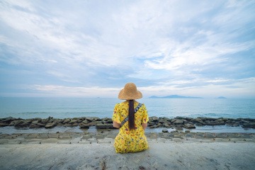 Frau in einem modischen Kleid sitzt am Meer