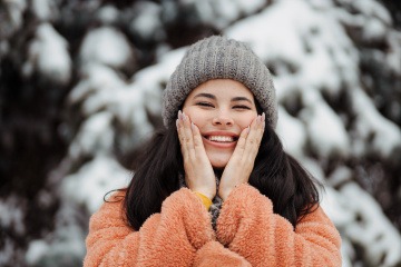 Junge Frau im Schnee und strahlt in die Kamera