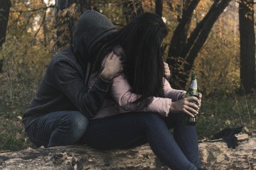 Zwei Personen halten eine Alkoholflasche in der Hand 