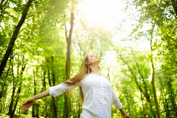 Eine Frau steht im Wald mit guter Laune im Frühling