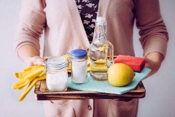 Zitronensäure Verwendung - junge Frau mit Zitrone und Putzmitteln